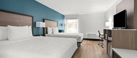 Una habitación de hotel con dos camas, un escritorio, una silla, un televisor y una ventana.