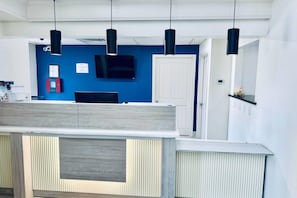A modern interior with a blue accent wall, a flat-screen TV, and pendant lighting. - Baymont by Wyndham Ardmore I-35 (Ardmore)