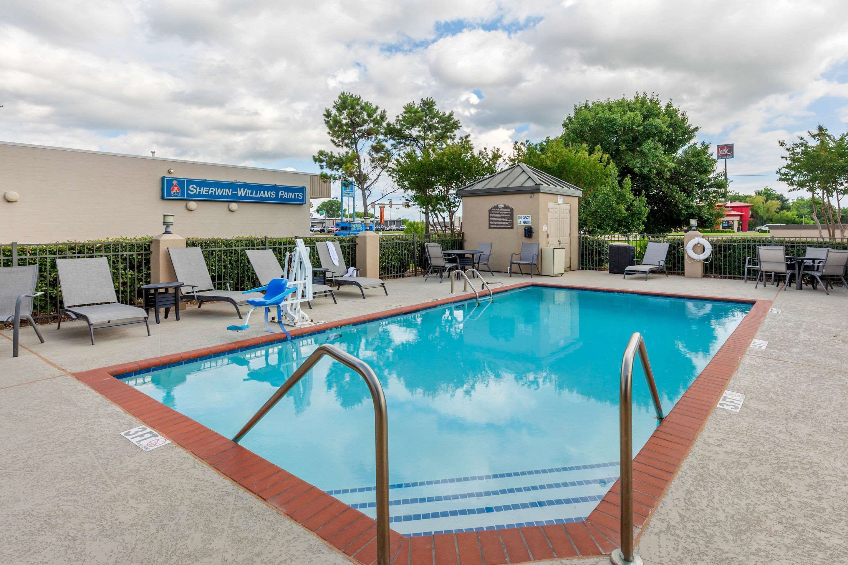 Una piscina con sillas de descanso y un pequeño pabellón.