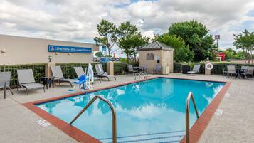 A swimming pool with lounge chairs and a small gazebo.