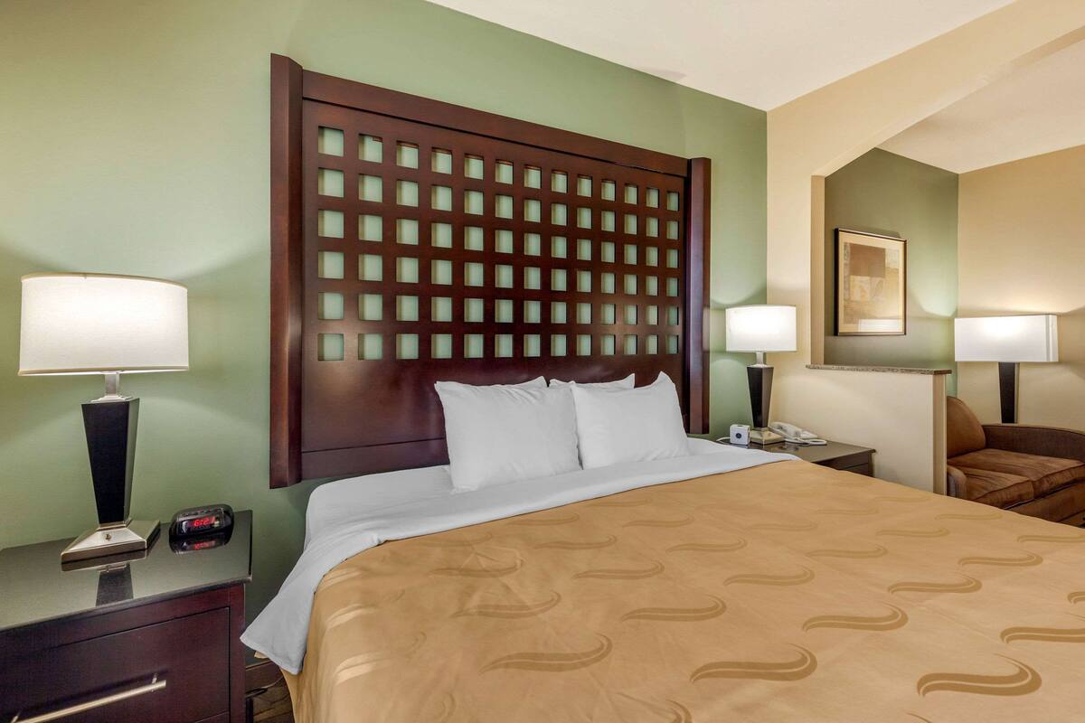 A hotel room with a large bed, two bedside tables, a nightstand, a chair, and a wall-mounted TV.