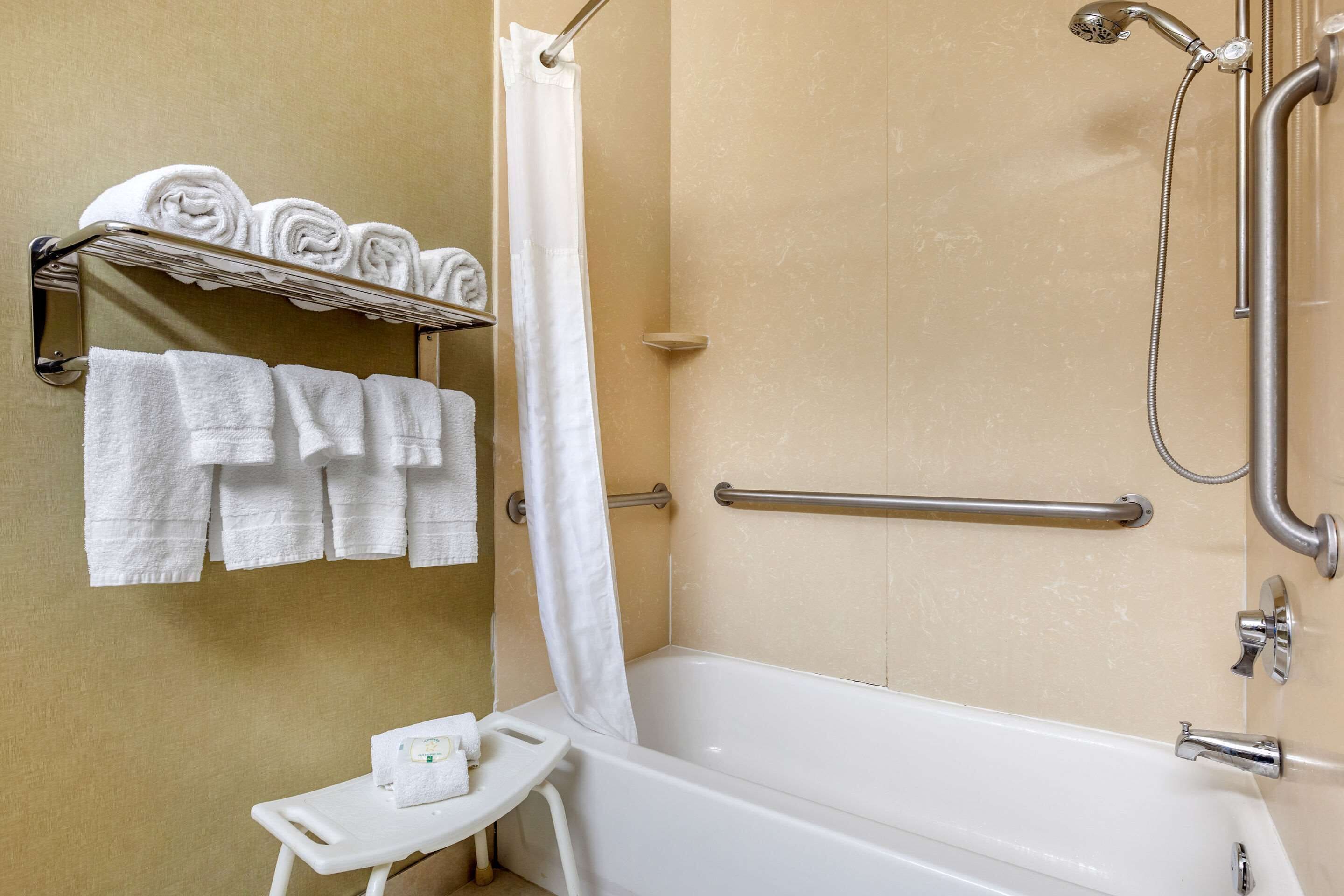 A bathroom with a bathtub, a shower, and a towel rack with neatly folded towels.