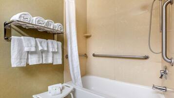 A bathroom with a bathtub, a shower, and a towel rack with neatly folded towels.