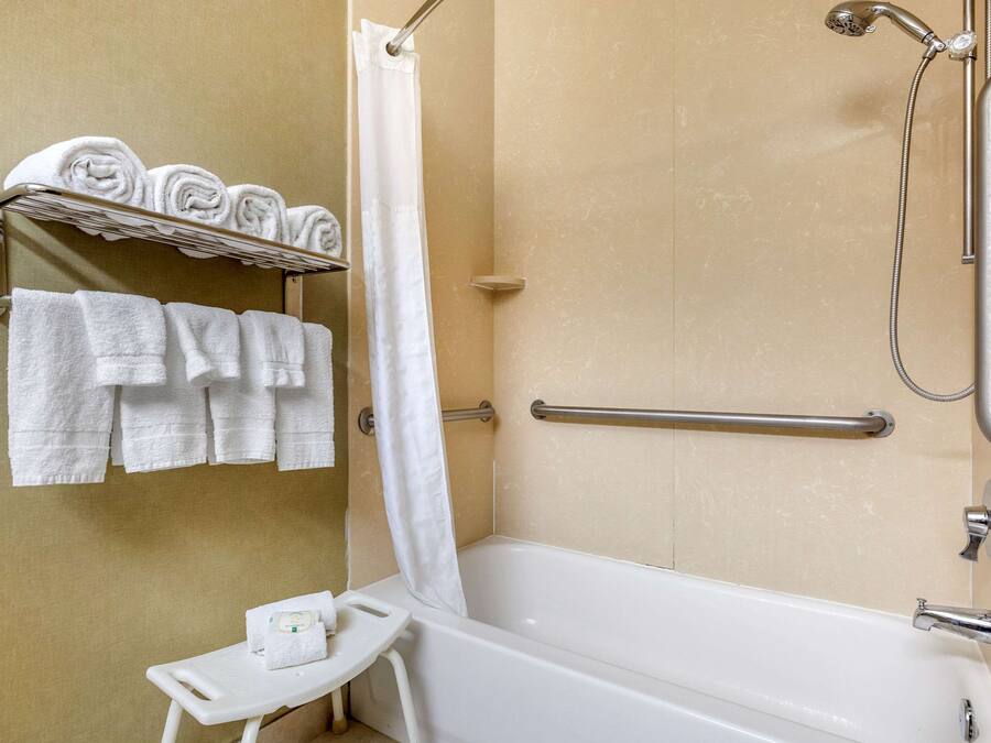 A bathroom with a bathtub, a shower, and a towel rack with neatly folded towels.