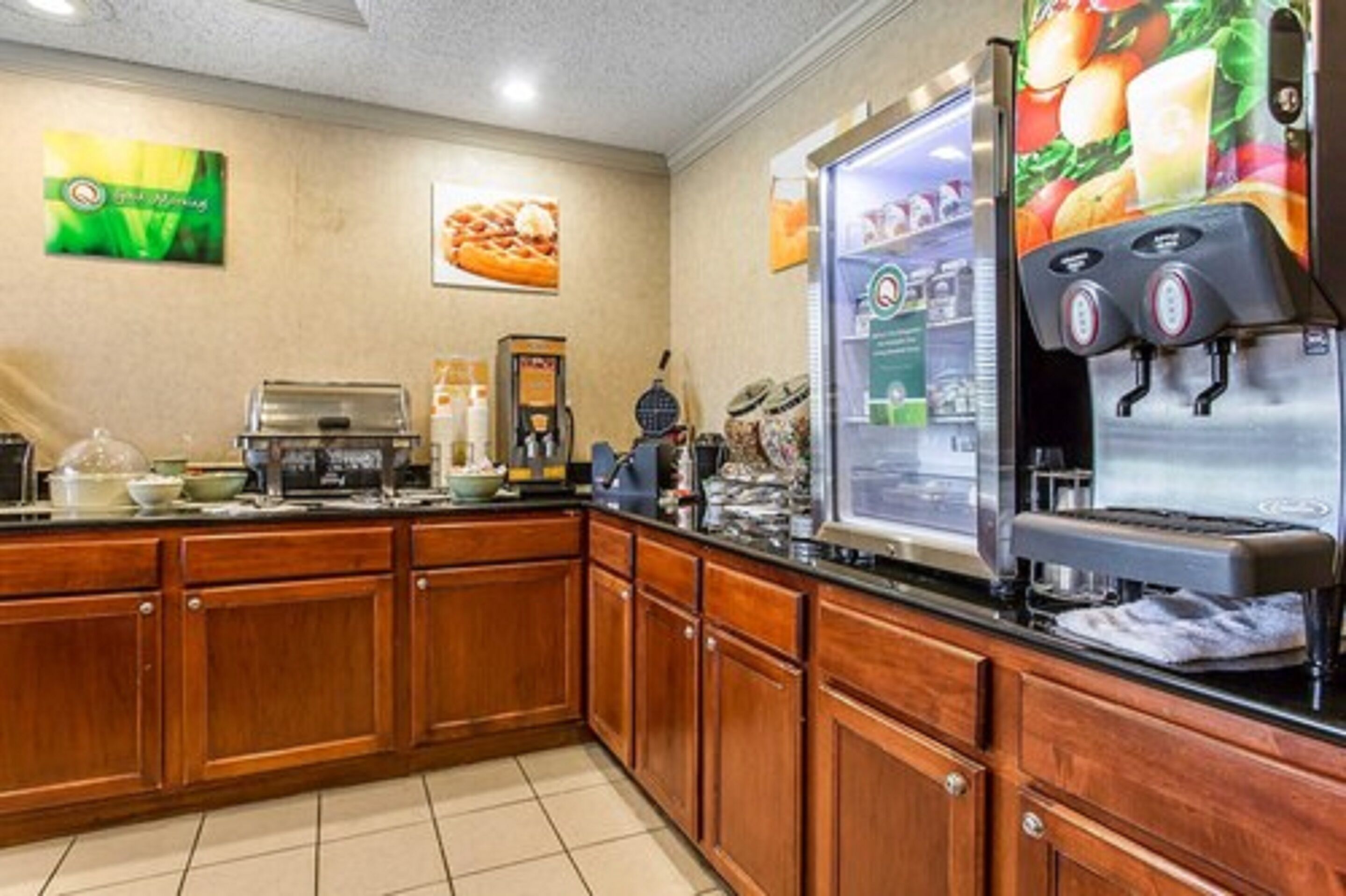 A kitchen with wooden cabinets, a coffee machine, and a refrigerator with a fruit display.