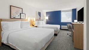 Une chambre d’hôtel avec deux lits, un bureau, une chaise et une fenêtre.