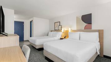 A hotel room with two beds, a desk, and a TV.