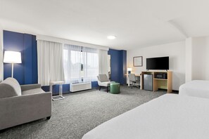 A hotel room with a bed, a sofa, a desk with a computer, a TV, and a window with curtains. - Spark by Hilton Muskogee (Muskogee)