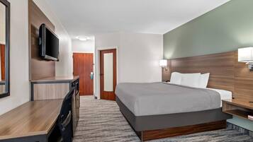 Ein Hotelzimmer mit Bett, Schreibtisch, Fernseher und Tür.