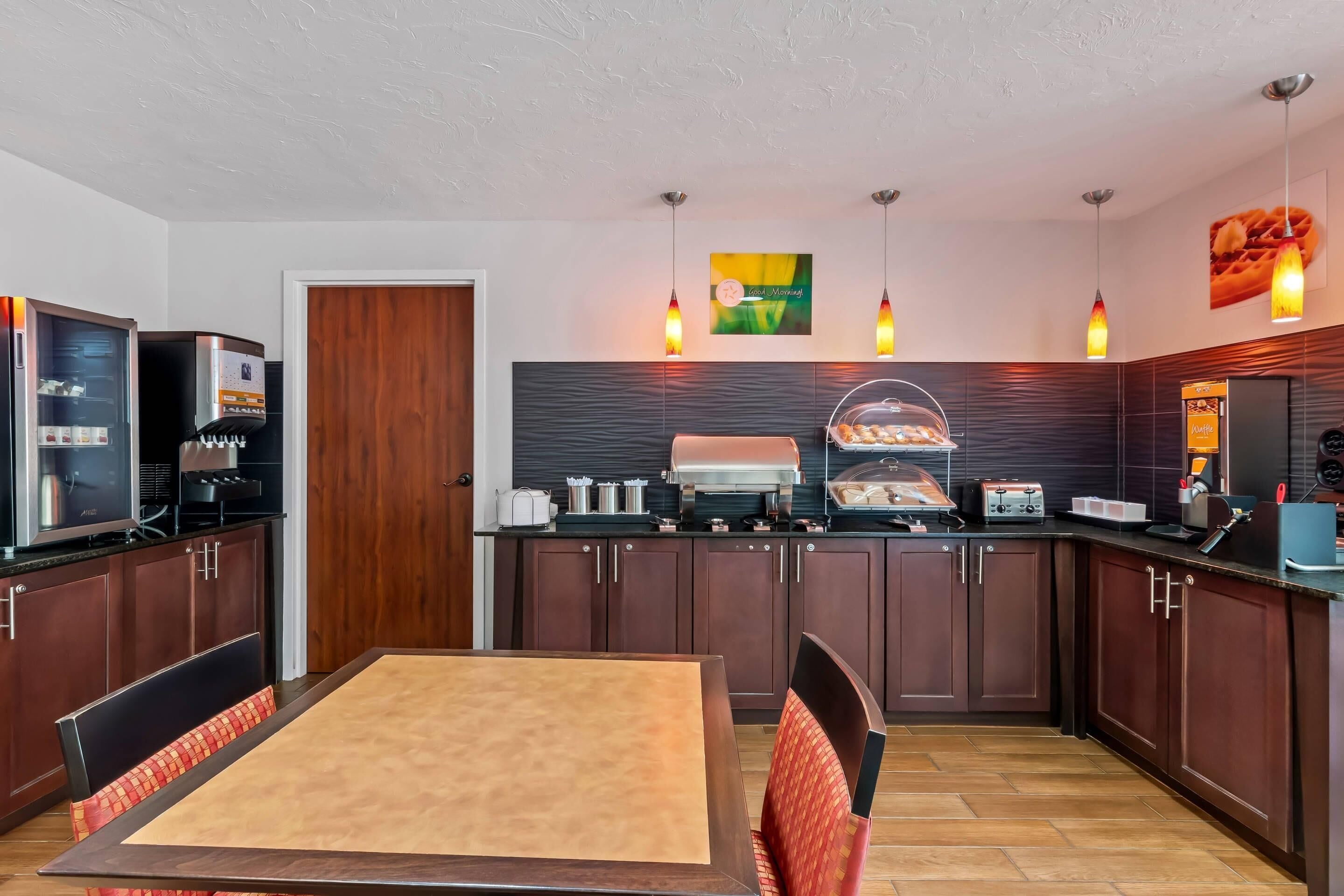 Una cocina moderna con armarios de madera oscura, una isla central con horno integrado e iluminación colgante.