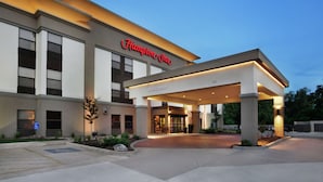 A Hampton Inn hotel with a modern facade, a welcoming entrance, and a parking area.