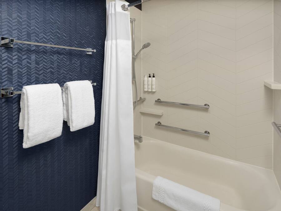 A bathroom with a bathtub, a shower, and a towel rack with two towels.