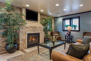 Una sala de estar con chimenea de piedra, un televisor de pantalla plana en la pared, una mesa de centro de cristal y un sofá de cuero.