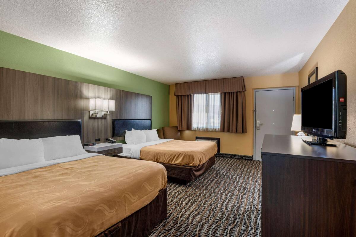 A hotel room with two beds, a television, a desk, and a wardrobe.