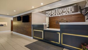 A modern reception area with a wooden accent wall, a flat-screen TV, and a decorative Christmas tree display. - Best Western Hermiston Inn (Hermiston)