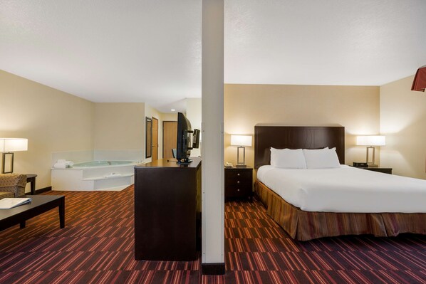 A hotel room with a bed, bedside table, lamp, and a large window.