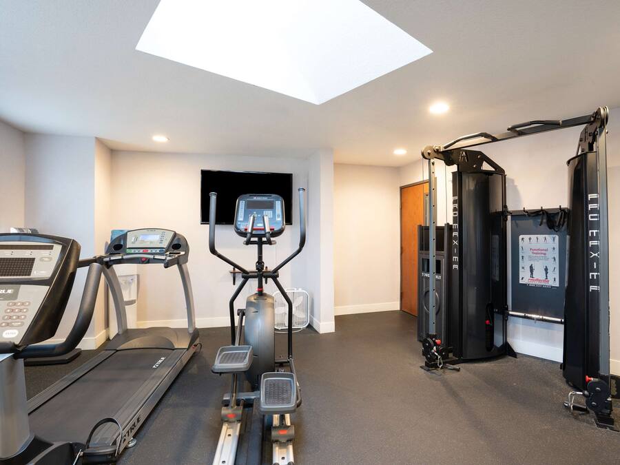Gimnasio en casa con cinta de correr, elíptica y equipo de levantamiento de pesas.