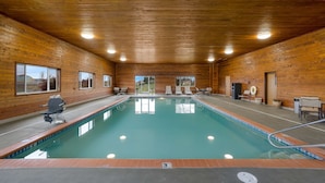 An indoor swimming pool with wooden walls and ceiling, surrounded by lounge chairs and a lifeguard stand. - Best Western Hermiston Inn (Hermiston)