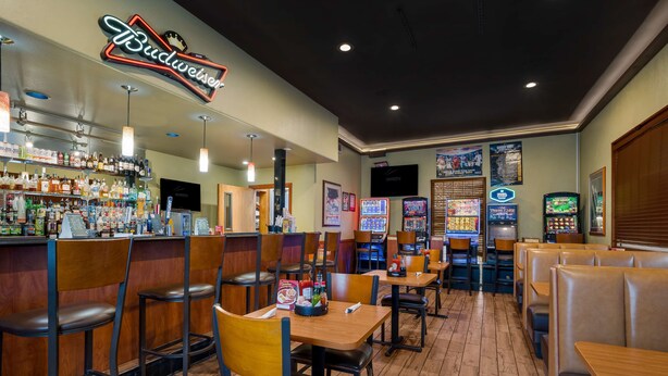 A restaurant interior with booths, tables, a bar area, and arcade games. - Best Western Hermiston Inn (Hermiston)