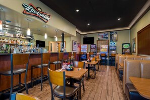 A restaurant interior with booths, tables, a bar area, and arcade games.