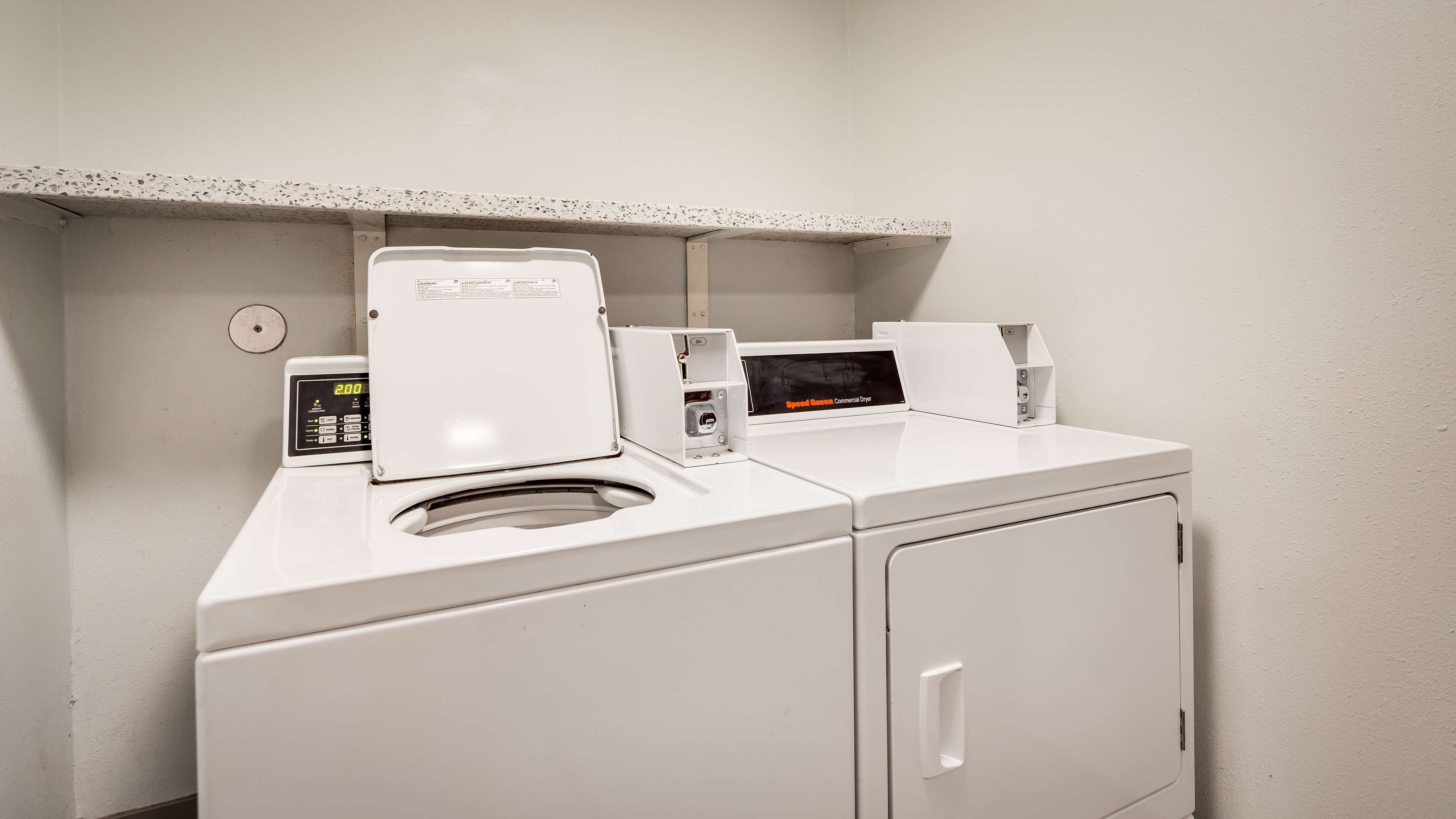 A laundry facility with a washing machine, dryer, and a control panel.