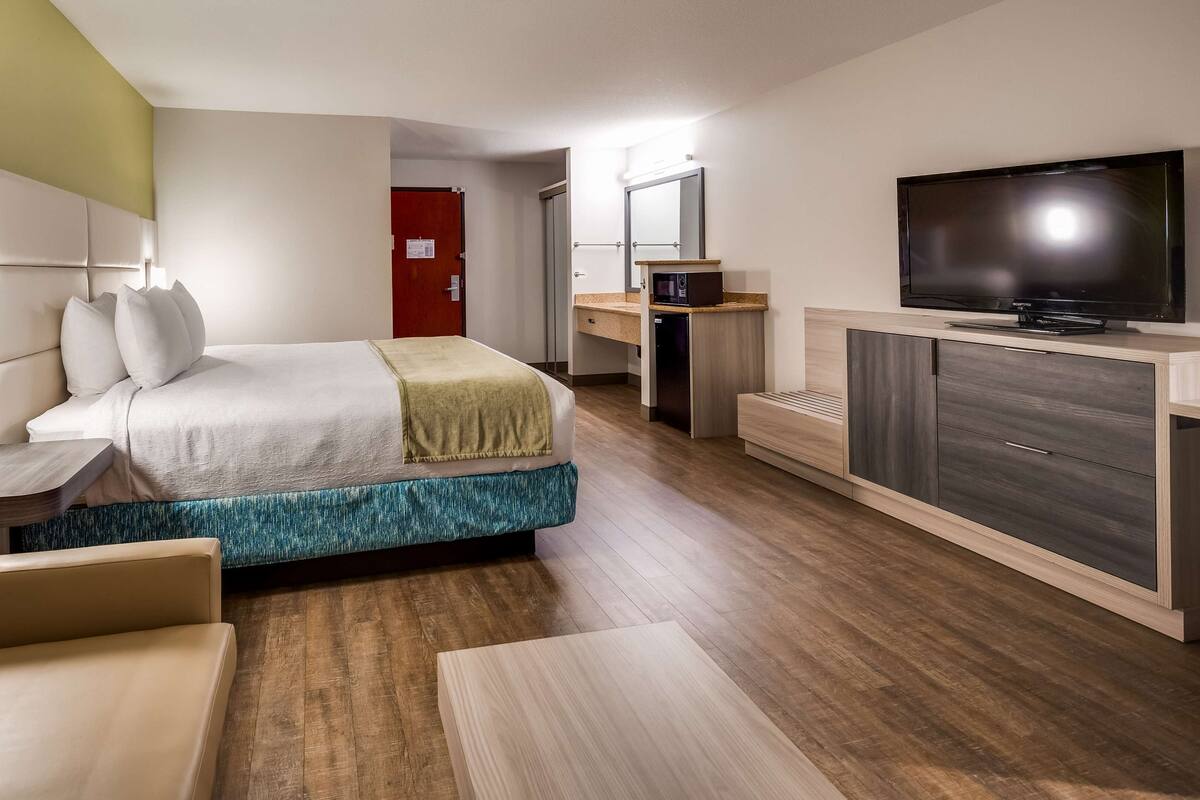 A hotel room with a bed, a TV, a desk, and a chair.