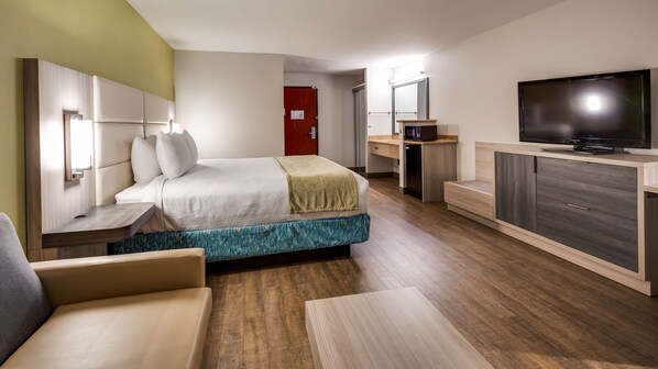 A hotel room with a bed, a TV, a desk, and a chair.