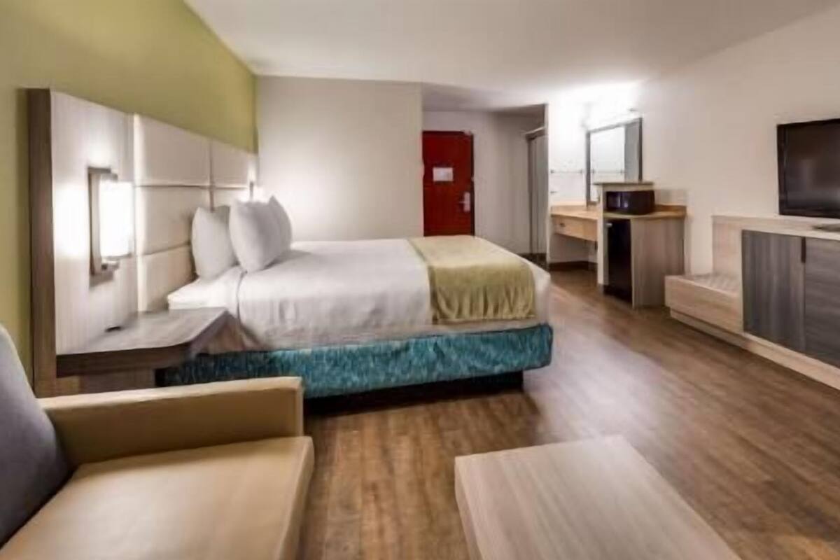 A hotel room with a bed, a TV, a desk, and a chair.
