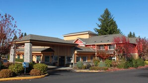 A hotel with a covered entrance, multiple windows, and a parking lot.