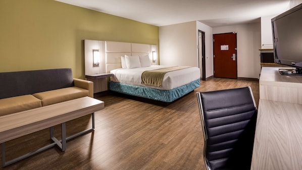 A hotel room with a bed, a sofa, a desk, and a chair.