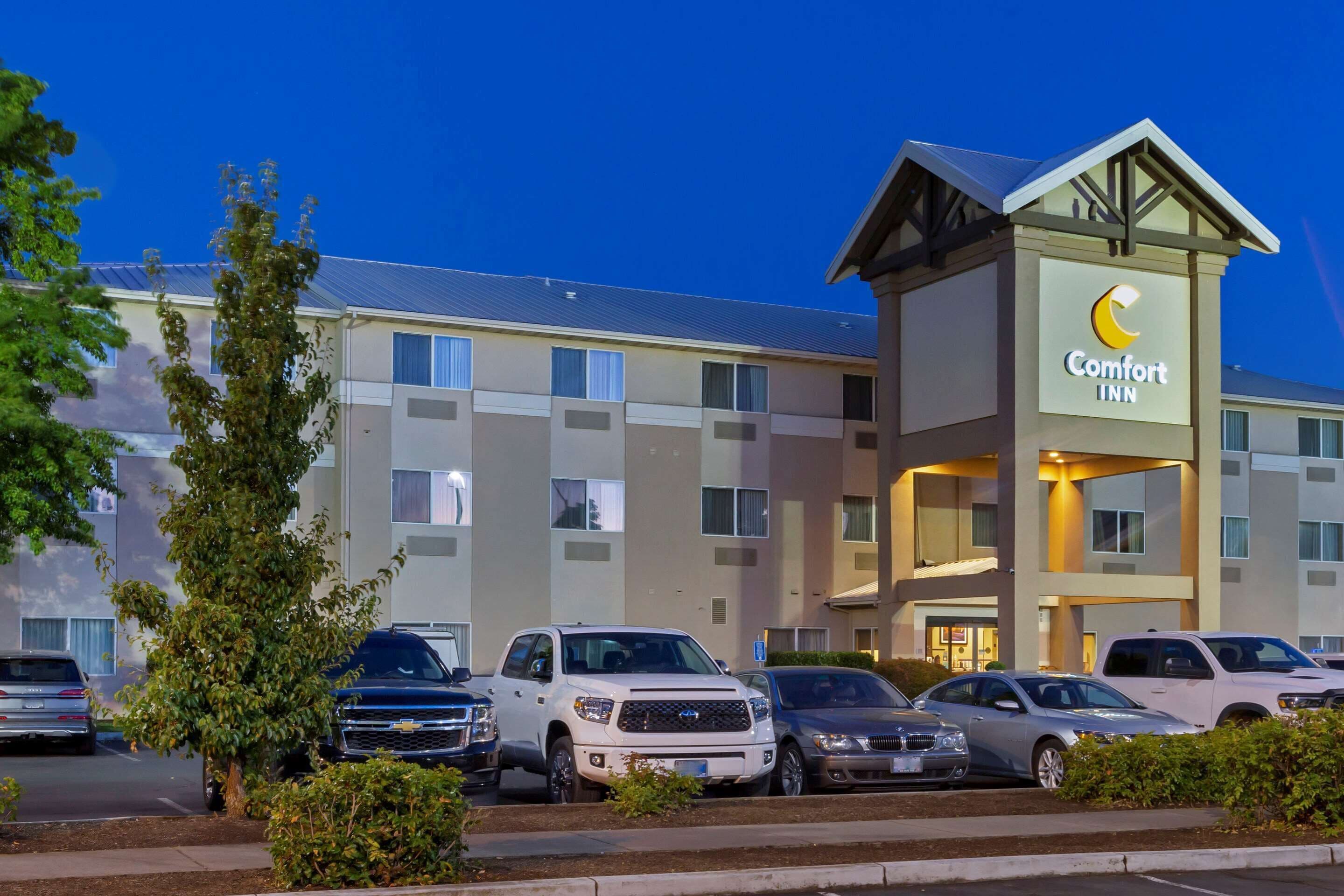 A Comfort Inn hotel with a modern design, featuring a prominent sign and multiple parking spaces.
