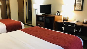 A hotel room with two beds, a desk with a television, a lamp, and a telephone.