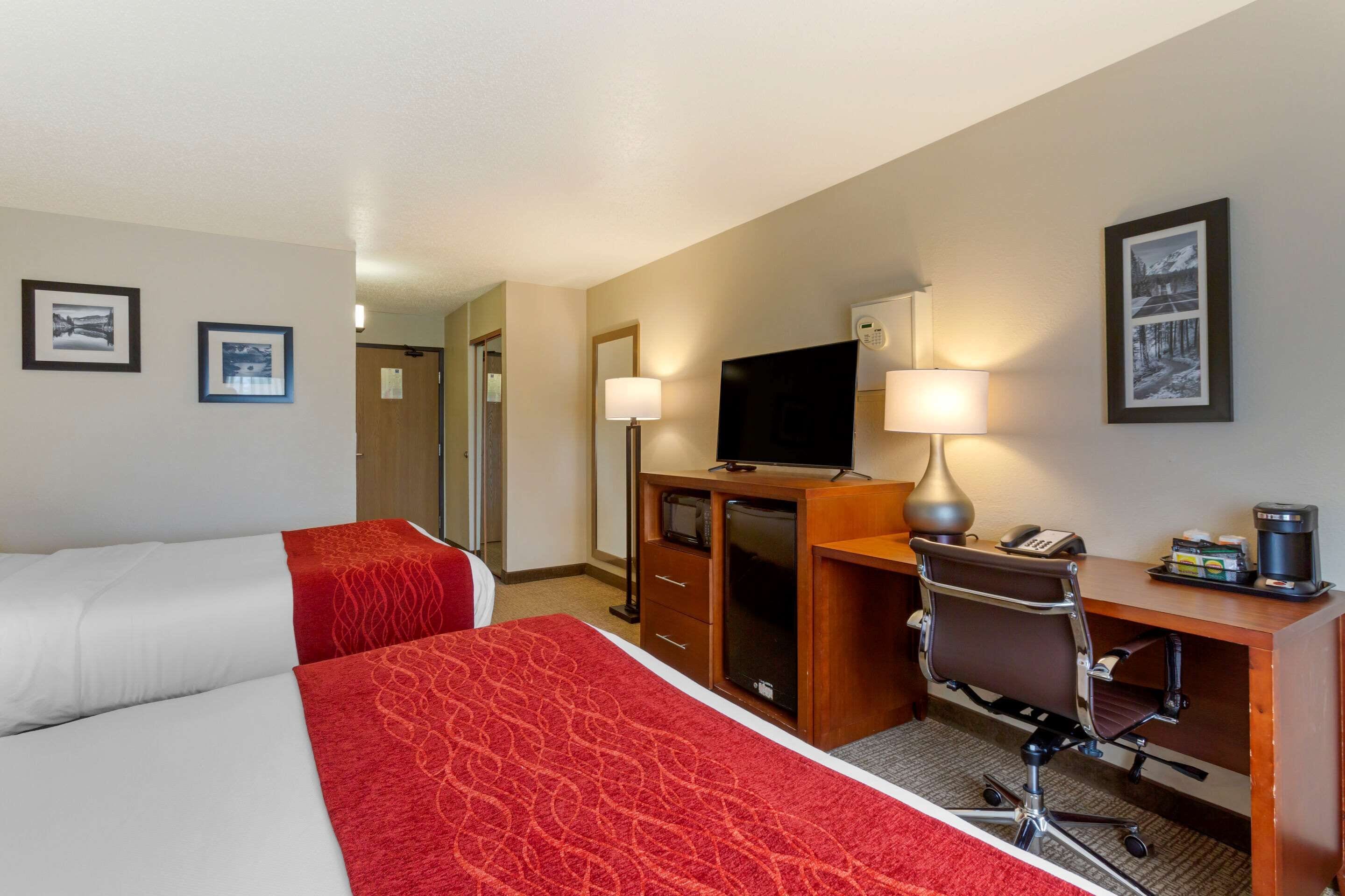 Une chambre d’hôtel avec deux lits, un bureau, une chaise, une télévision, une lampe et une machine à café.