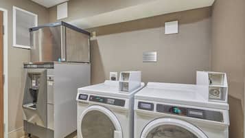 Un centro de lavandería con refrigerador, dispensador de hielo y dos lavadoras de carga frontal.