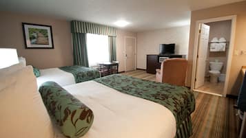 A hotel room with two beds, a desk, a television, and a bathroom visible through an open door.