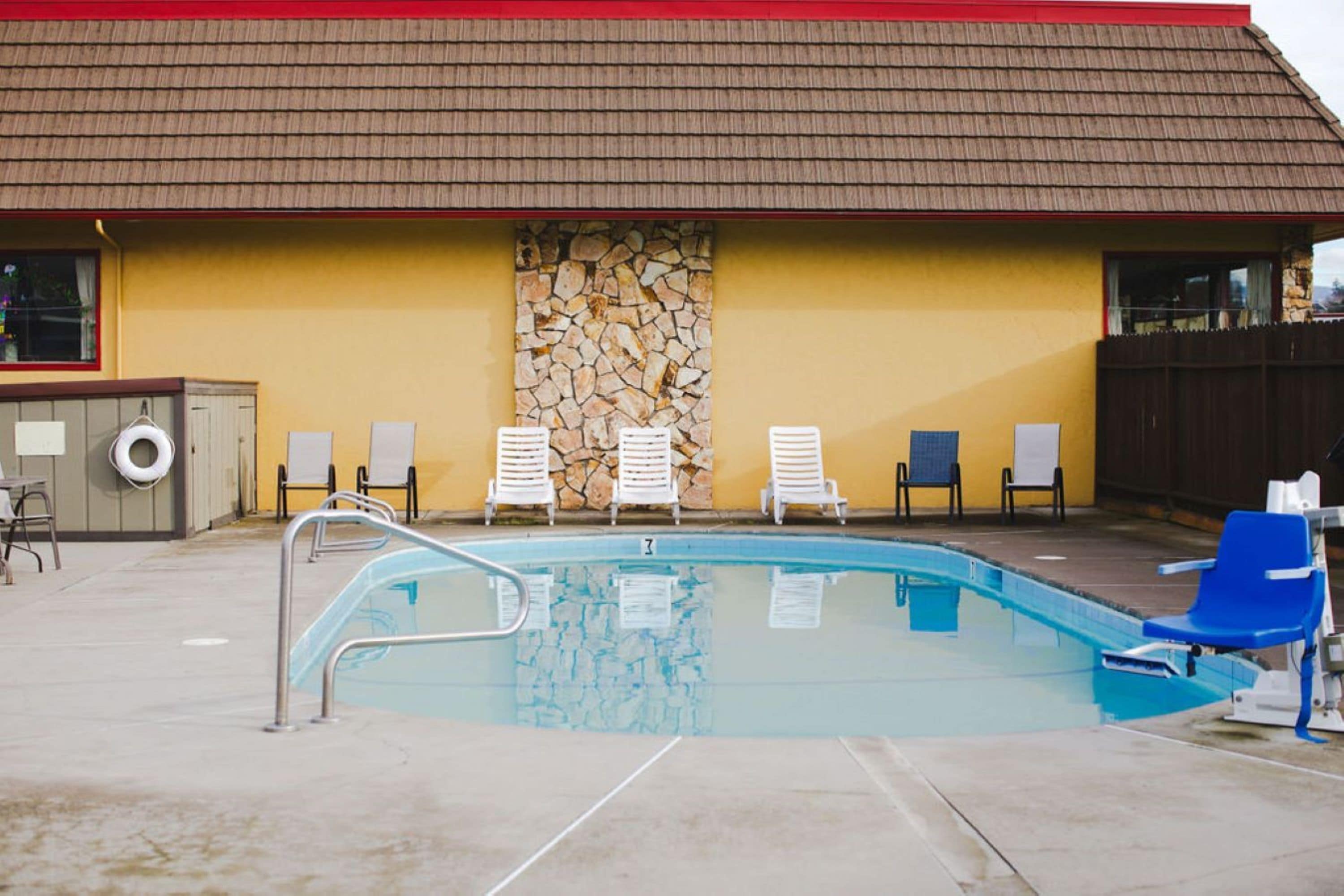 A swimming pool with lounge chairs and a stone wall.