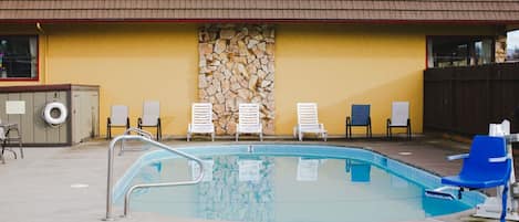 A swimming pool with lounge chairs and a stone wall.