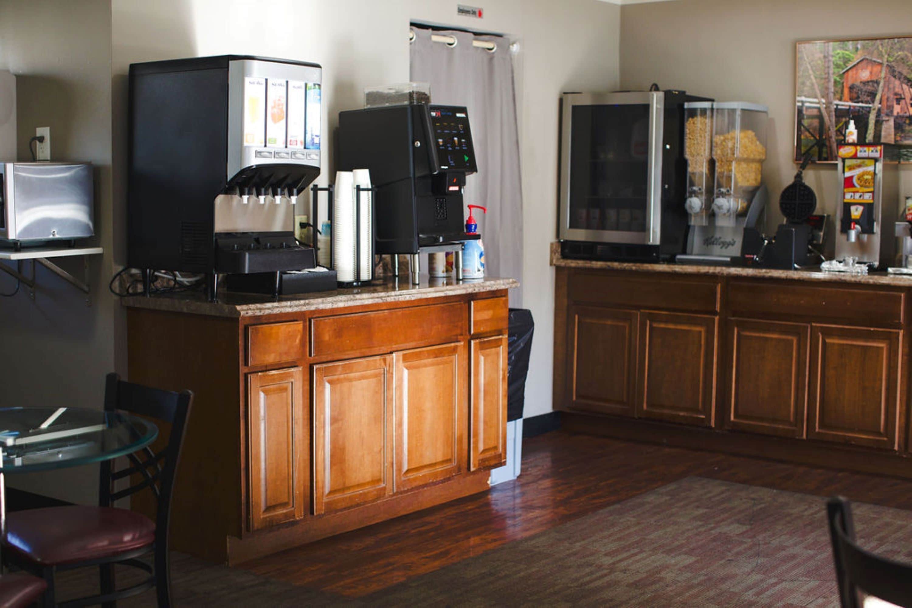 A compact kitchen with a coffee machine, a refrigerator, and a microwave.