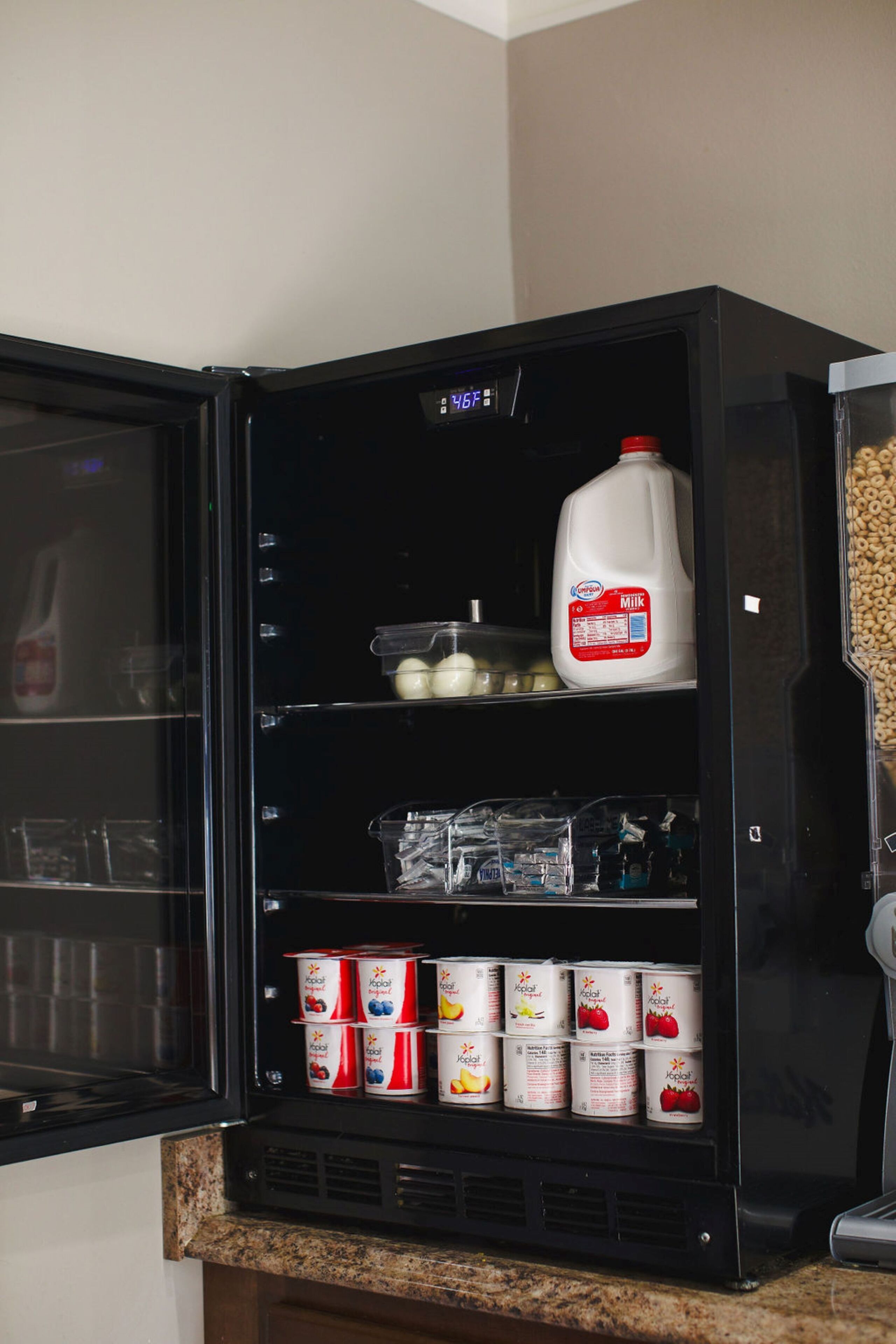 A refrigerator stocked with milk, eggs, and canned beverages.