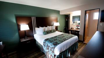 A hotel room with a bed, bedside lamps, a dresser, a mirror, and a television.