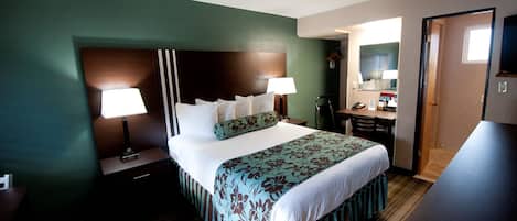 Een hotelkamer met een bed, nachtlampjes, een dressoir, een spiegel en een televisie.