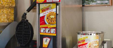 A waffle maker with a syrup dispenser and a waffle iron.