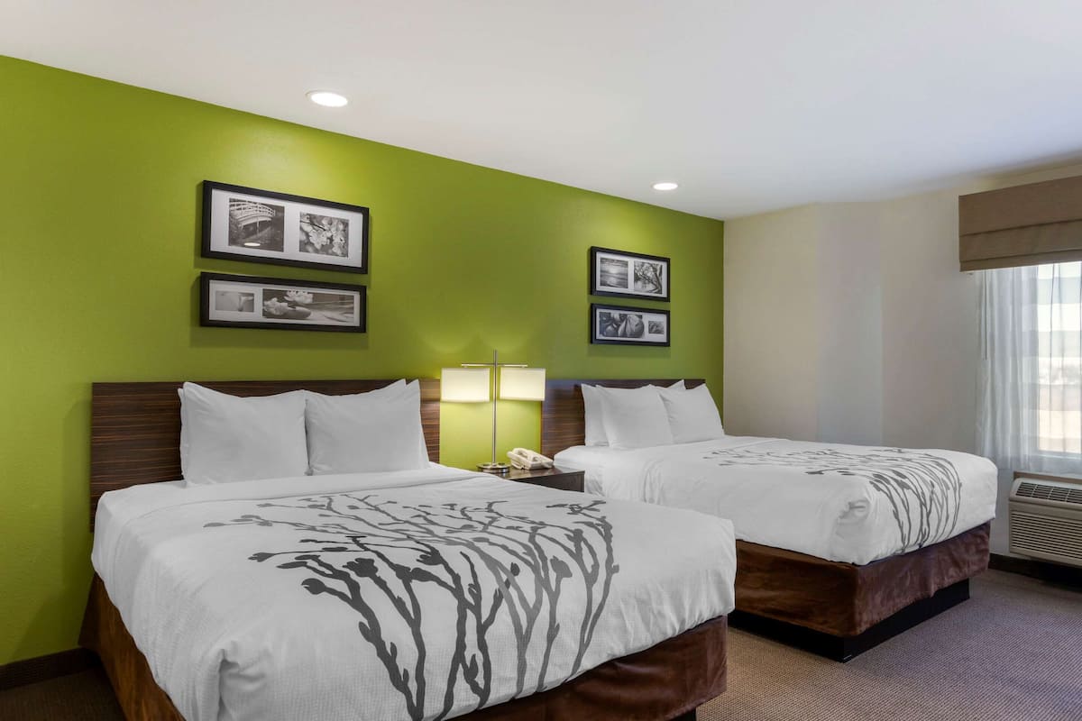 A hotel room with two beds, green walls, and framed pictures on the wall.