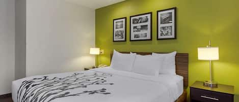 A hotel room with a large bed, two bedside tables with lamps, and three framed pictures on the wall.