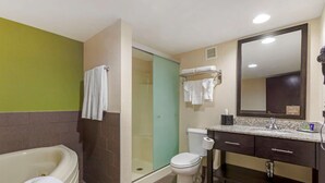 A bathroom with a bathtub, toilet, shower, and a vanity with a mirror.