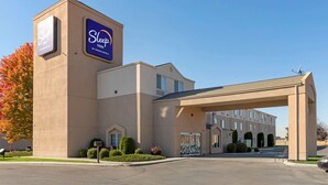 A Sleep Inn hotel with a beige facade, a prominent sign, and a covered entrance.