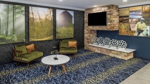 A modern lounge area with a stone fireplace, comfortable seating, and large nature-themed wall art. - Fairfield Inn & Suites by Marriott Butler (Butler)