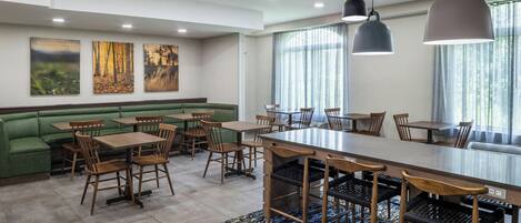 A restaurant with a long counter, booths, and a green seating area.