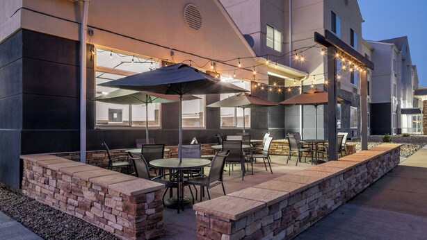 An outdoor patio area with tables and chairs, string lights, and a stone wall. - Fairfield Inn & Suites by Marriott Butler (Butler)