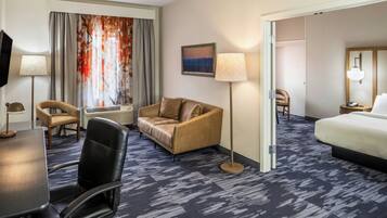 Habitación de hotel con sofá, escritorio, silla, cama y televisión.
